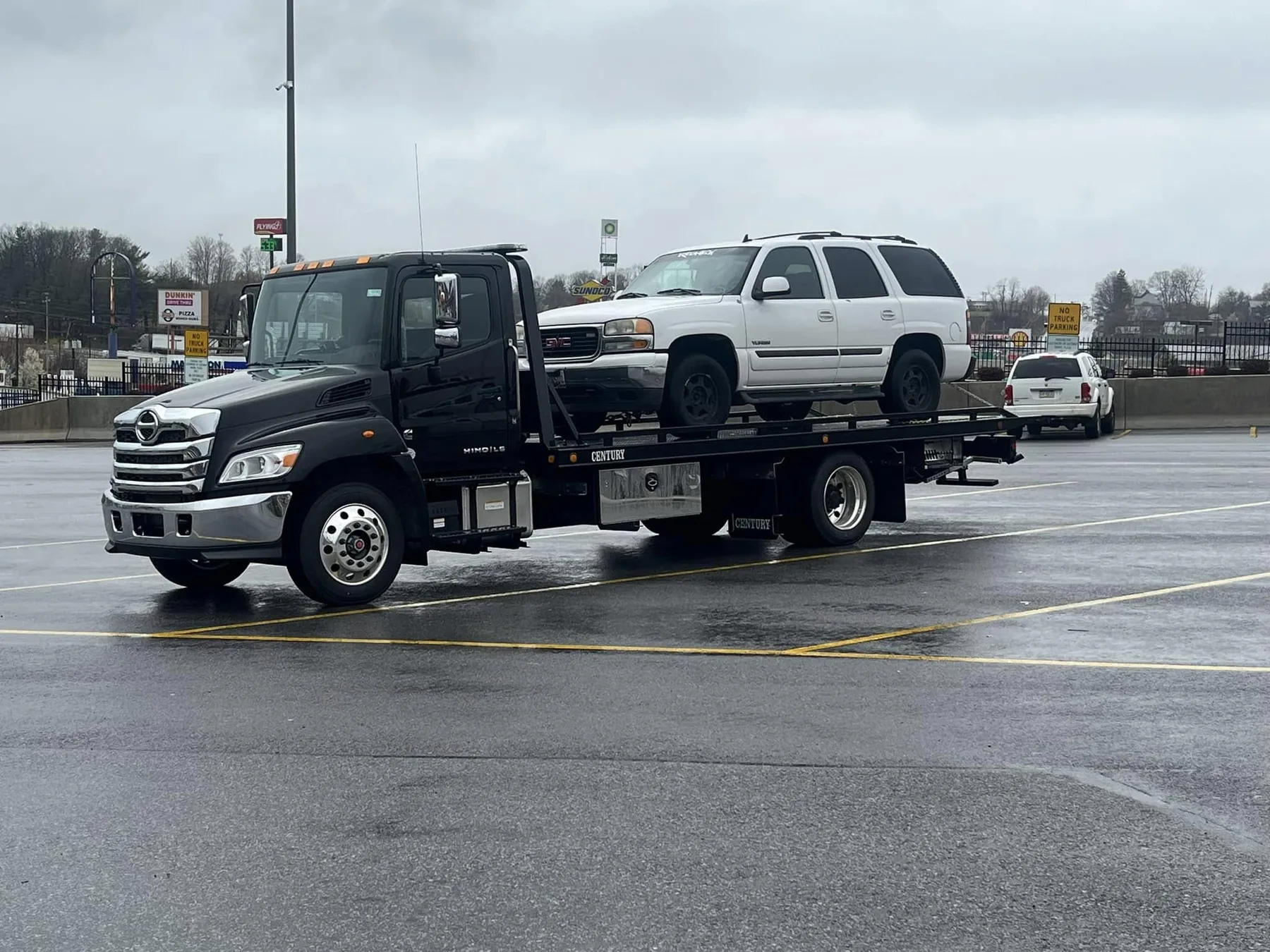 Black Statewide Recovery Service flatbed tow truck carrying a white SUV